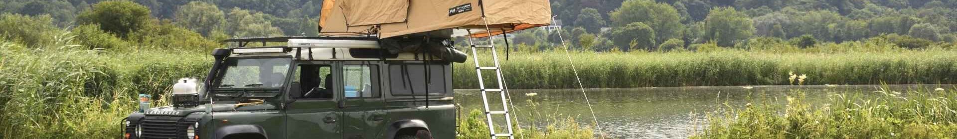 Man en vrouw bij hun auto aan het barbecueën