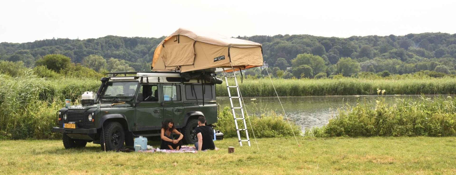 Man en vrouw bij hun auto aan het barbecueën