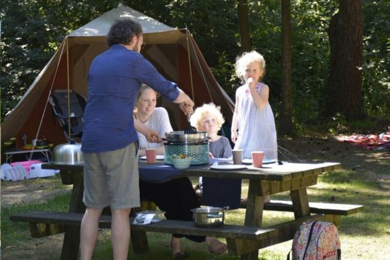 Gezin op de camping aan het barbecueën